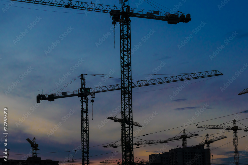 Construction cranes on sunset