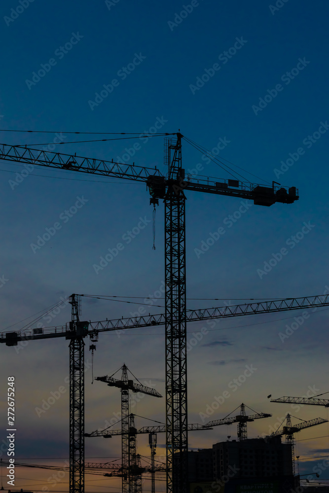 Construction cranes on sunset