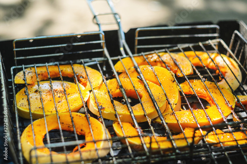 Baked pumpkin slices on the grill grid. The process of cooking vegetables on the grill in the open air