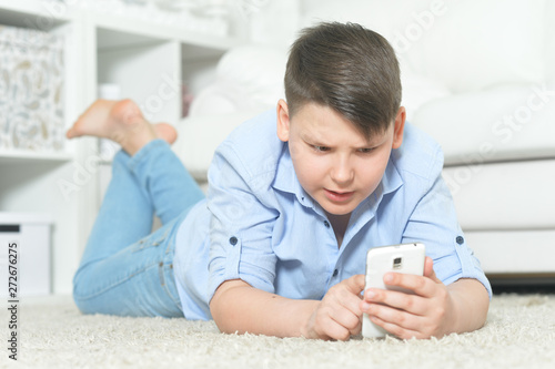 Young boy with smartphone playing the game at home