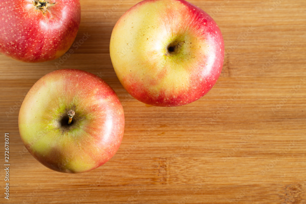 three beautiful red-yellow apples lying on a wooden triangle background three beautiful red-yellow apples lying on a wooden triangle background
