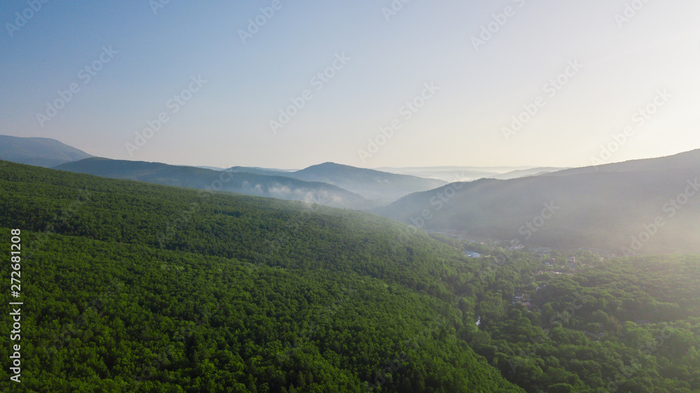 Aerial view of Caucasus mountain with haze and forest. Morning fog over the forest.