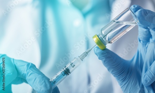 Medical blue hand holding syringe and vaccine