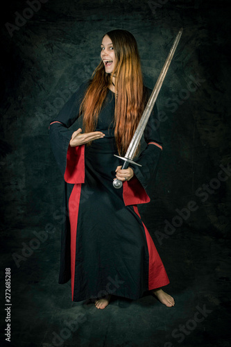 Standing woman in medieval clothing presenting a sword © Jens Hertel