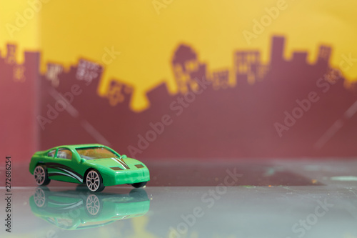 Fototapeta Naklejka Na Ścianę i Meble -  Green saloon car toy selective focus on blur city background