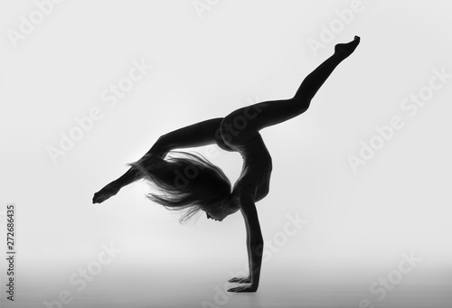 Gymnast with long hair and legs standing on hand in the string