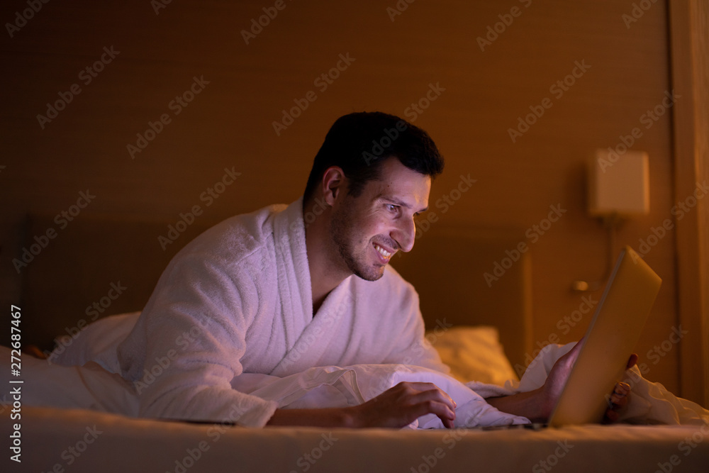 Man chatting on laptop in bed instead of sleeping, late night