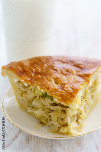 Cabbage pie on a porcelain plate. High resolution, white wooden background