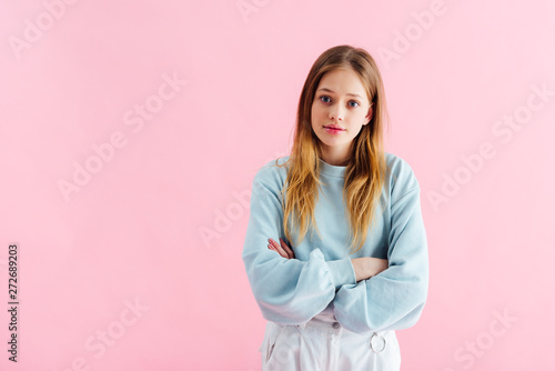 offended teenage girl with crossed arms isolated on pink photo