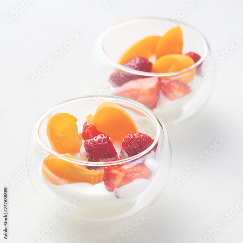 Light vitamin healthy dessert of sliced strawberry, apricot and cornflakes with cream in glass creamers