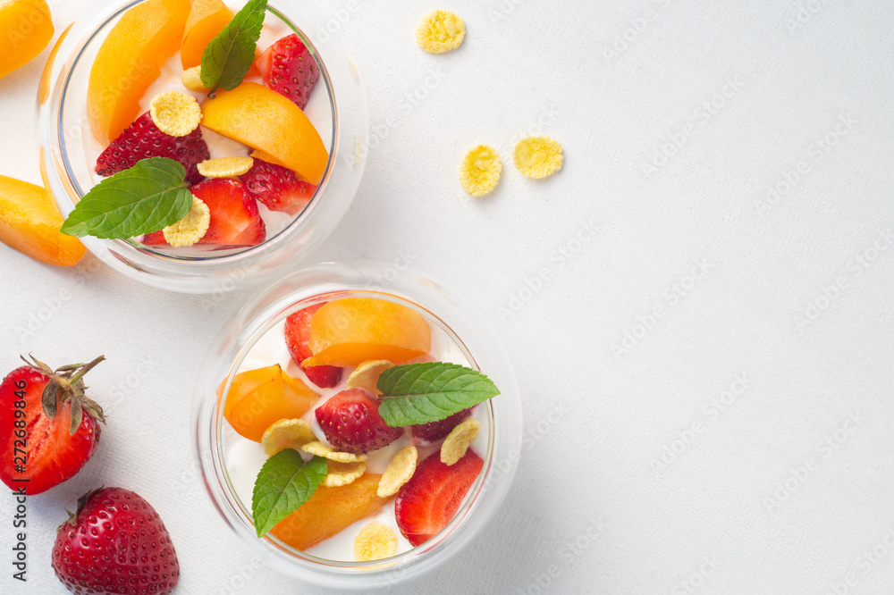Vitamin dessert of fresh strawberries, apricots and cornflakes with cream on a white background Vitamin dessert of fresh strawberries, apricots and cornflakes with cream on a white background