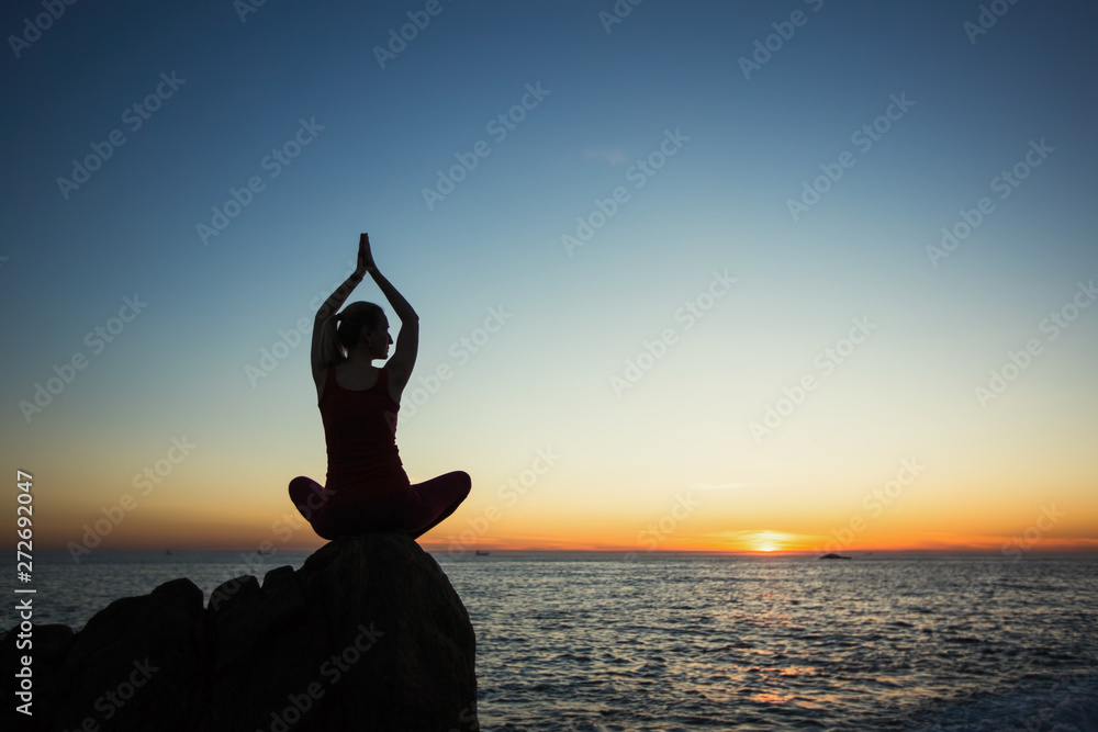 Yoga silhouette young woman on the beach at amazing sunset.