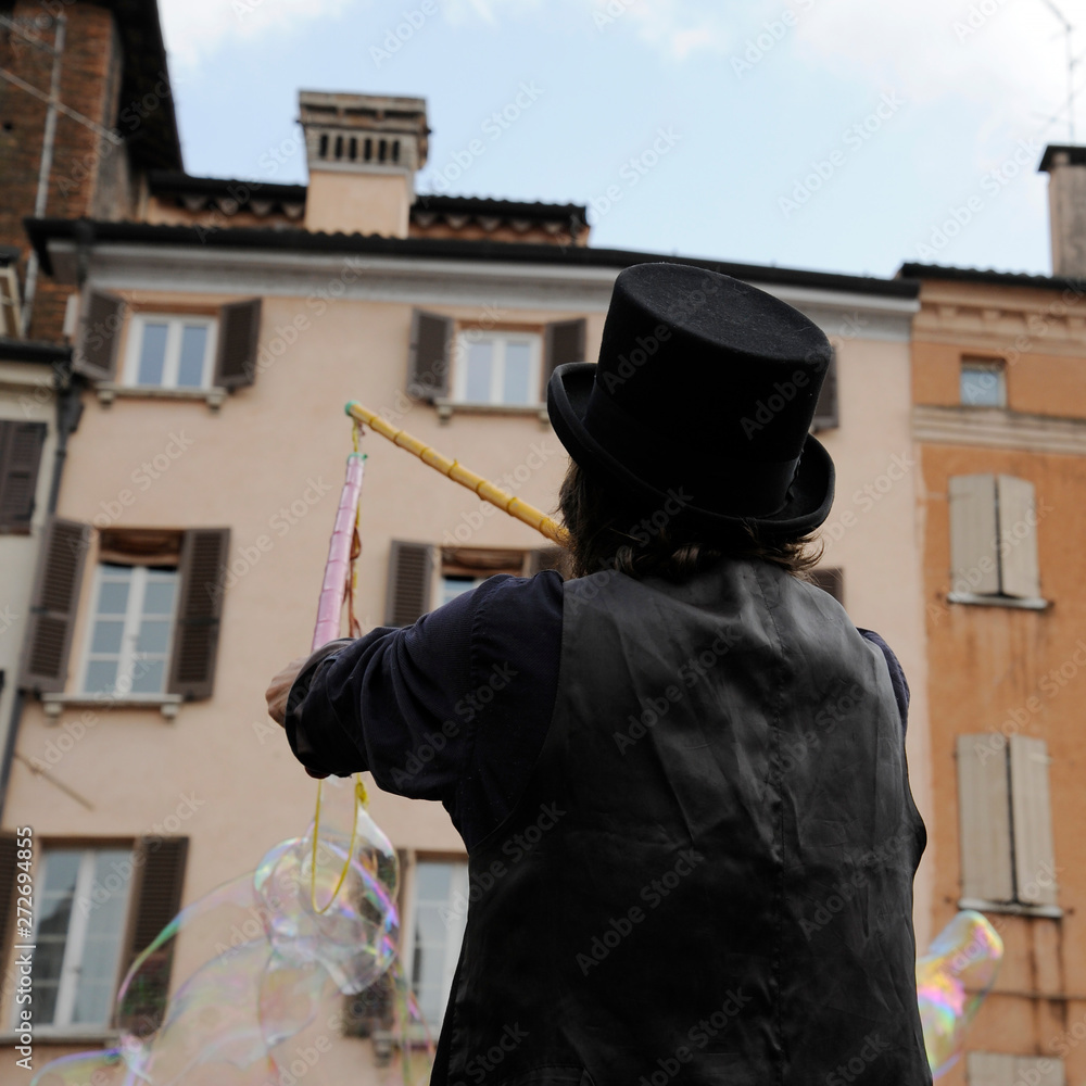 Man artist with black hat who make soap bubbles. Soap bubble show on the street.