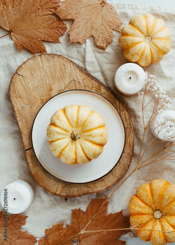 Top view of small pumpkin on a plate decorated Autumn ornate. The concept of table setting for Thanksgiving dinner and cooking.