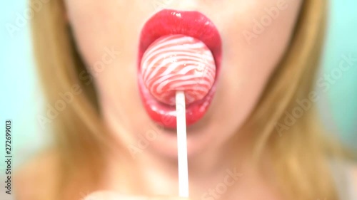 close-up, female sexy lips with red lipstick suck big pink round lollipop. copy space. blue background
