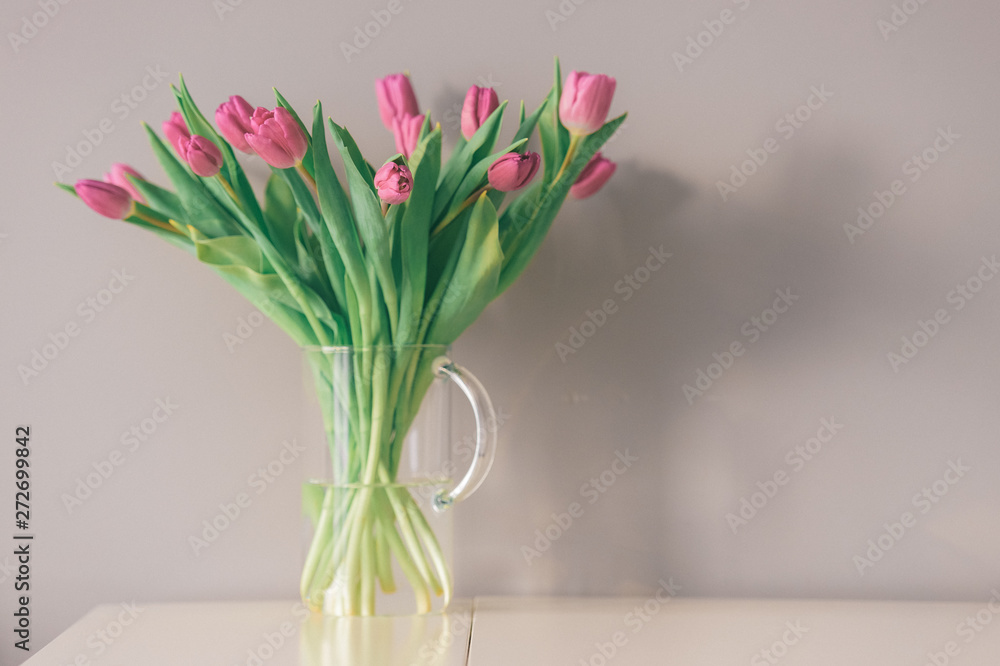 Glass vase with bouquet of beautiful tulips on grey wall background. Glass vase with bouquet of beautiful tulips on grey wall background.