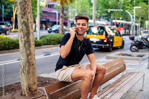 Young fashionable handsome man on the street of modern city talking on a cell phone. Communication concept