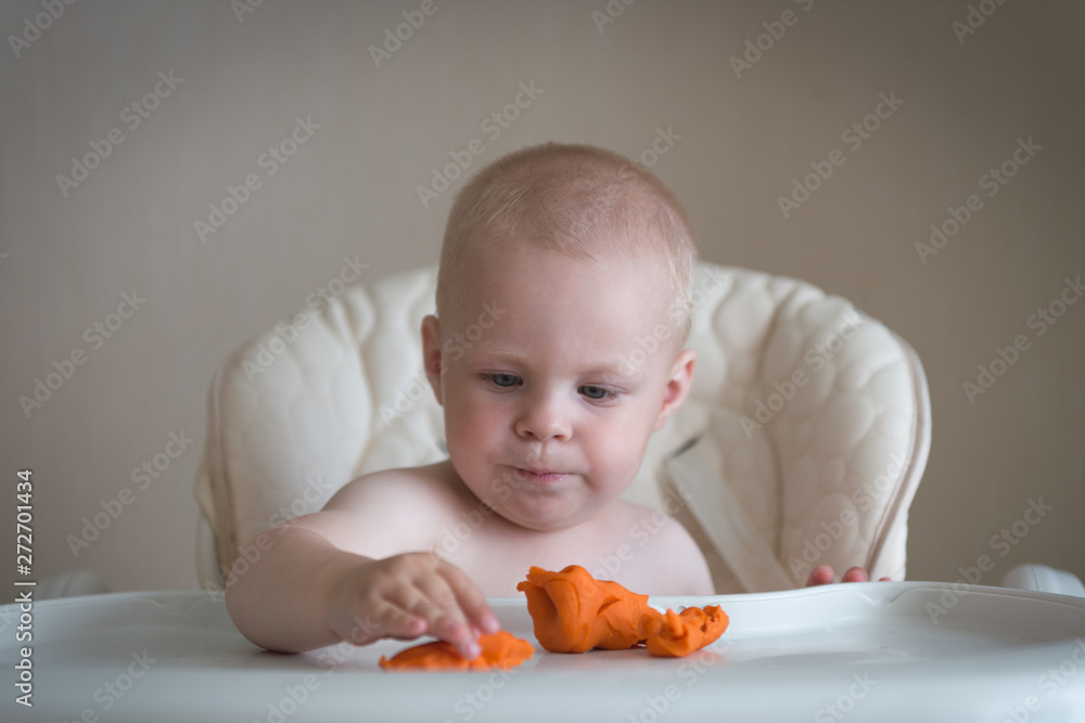 Children creativity. the baby is trying to sculpt from clay. Cute little boy mould from plasticine on table Children creativity. the baby is trying to sculpt from clay. Cute little boy mould from plasticine on table