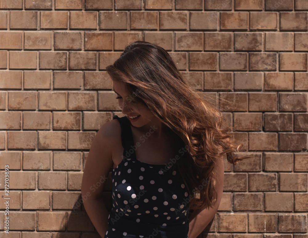 Outdoor portrait of young brunette women leaning on brick wall during sunny day. Outdoor portrait of young brunette women leaning on brick wall during sunny day.
