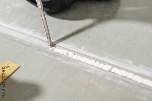 Worker is using a polyurethane foam for gluing drywall at ninety degrees. Hand holding polyurethane expanding foam glue gun applicator photo