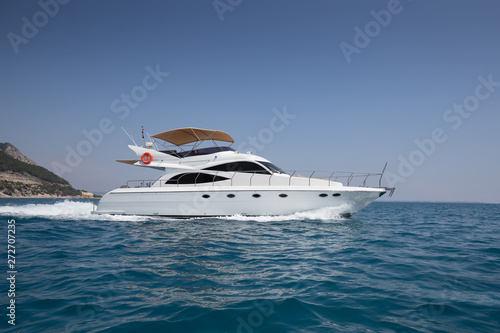 A luxurious powerboat cruising through beautiful blue waters.Side View