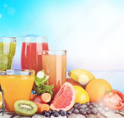 Composition of fruits and glasses of juice on blurred natural background
