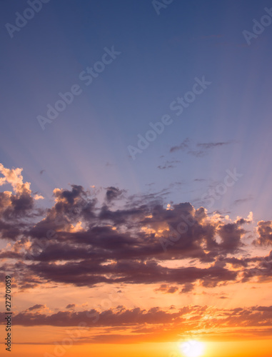 Beautiful sunrise with clouds of different colors and the rays of the sun against the blue sky. © Sviatoslav Khomiakov
