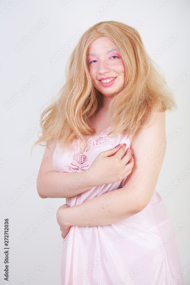 Charming plus size blonde asian girl in pink pretty silk nightgown standing and happy posing on white background in Studio alone. Chubby attractive woman in cute dress. Charming plus size blonde asian girl in pink pretty silk nightgown standing and happy posing on white background in Studio alone. Chubby attractive woman in cute dress.