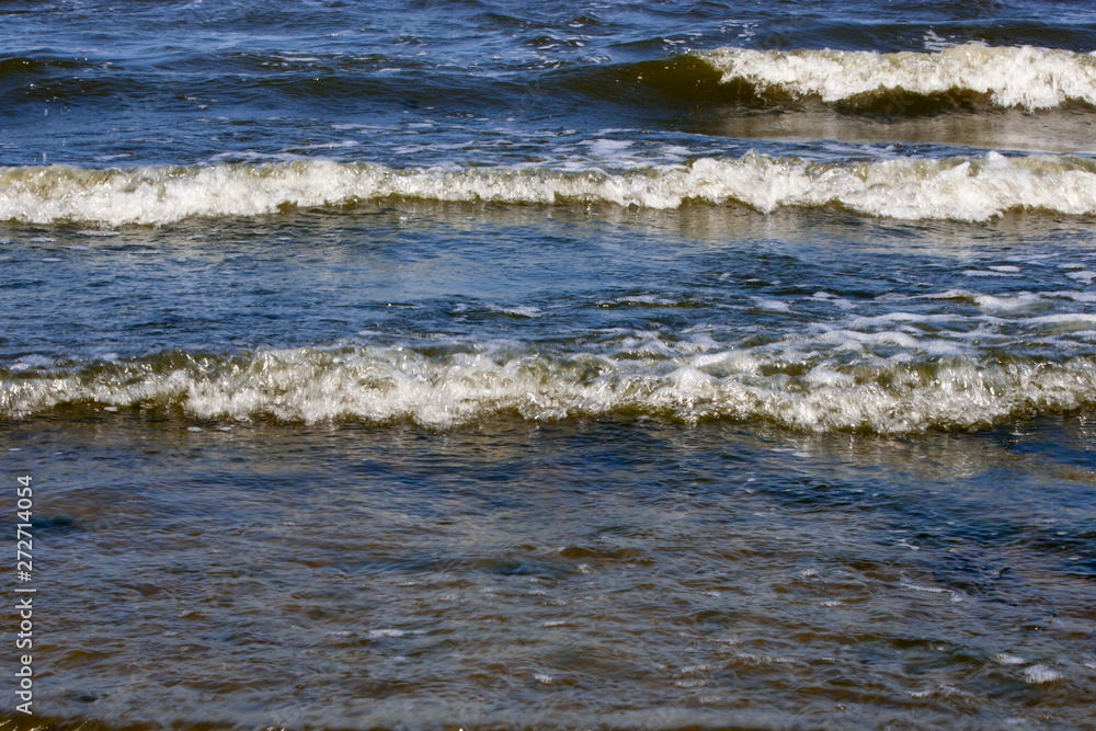 Waves with foam on the sea on the shore in summer Waves with foam on the sea on the shore in summer