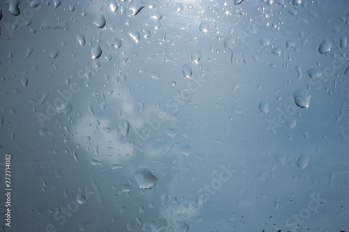 Abstraction of droplets on glass in the rain in gray-blue tones