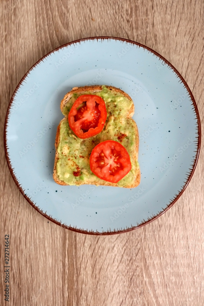 Toast with mashed avocado, cherry tomato and smoked pepper. Top view.