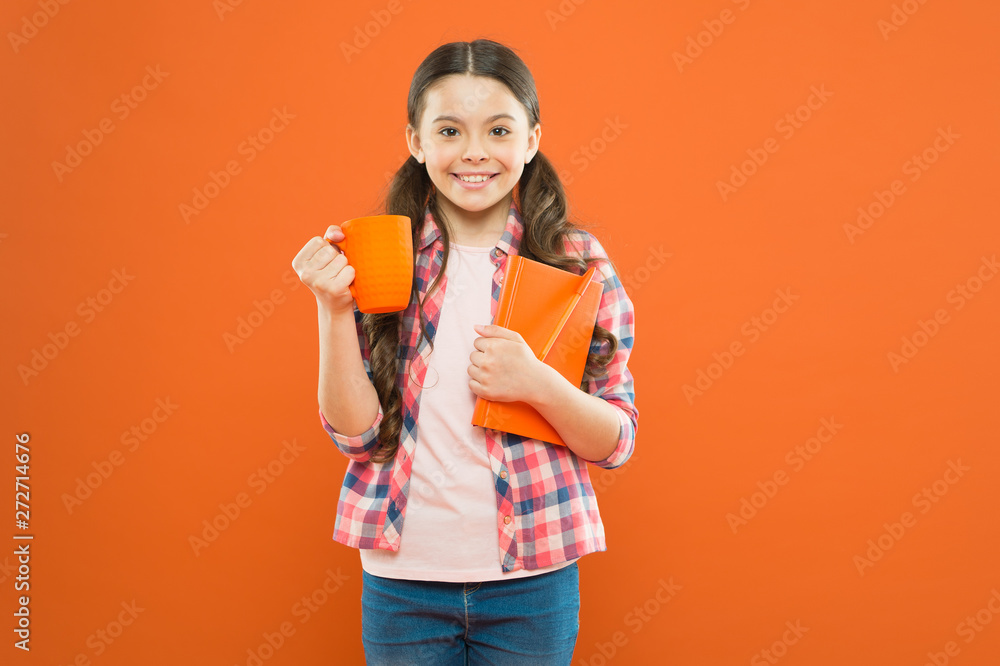 First thing in the morning. Small girl enjoying her energetic morning drink on orange background. Little kid drinking morning tea or milk. School child having breakfast in morning First thing in the morning. Small girl enjoying her energetic morning drink on orange background. Little kid drinking morning tea or milk. School child having breakfast in morning