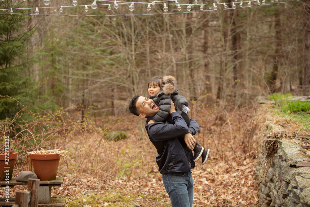 Fototapeta premium Side view of cheerful father carrying daughter while standing against bare trees in forest