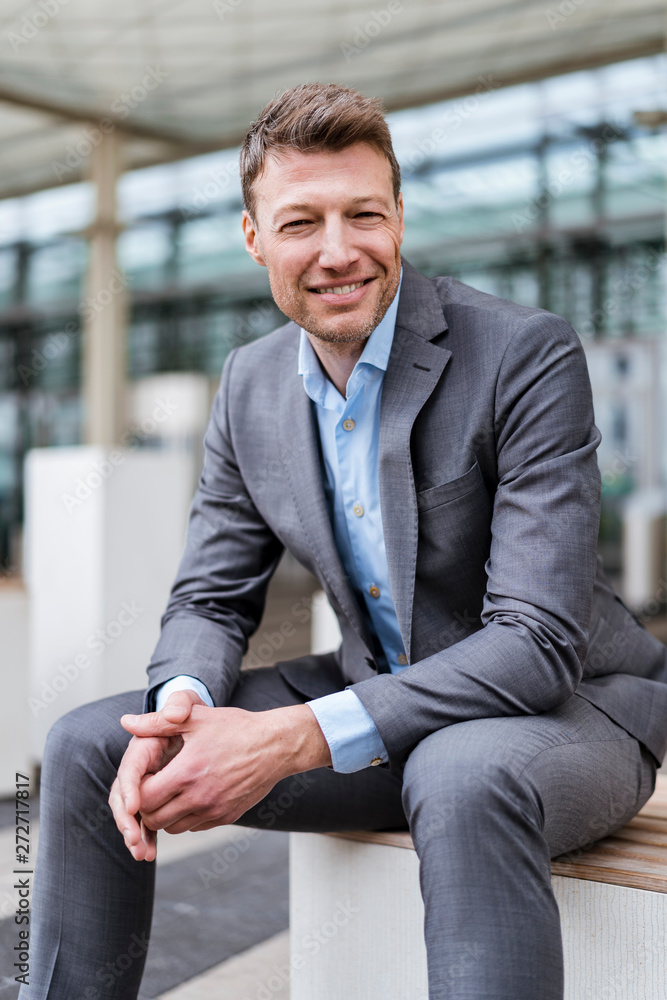 Portrait of smiling businessman sitting outside in the city Portrait of smiling businessman sitting outside in the city
