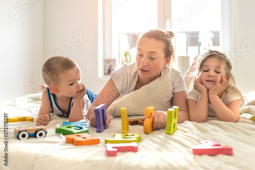 Mother playing educational toys with kids at home and enjoying the day together