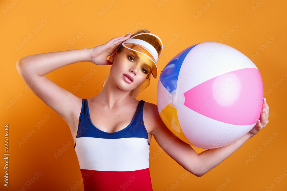 beautiful young blond woman posing in swimsuit and yellow plastic visor with inflatable ball beautiful young blond woman posing in swimsuit and yellow plastic visor with inflatable ball