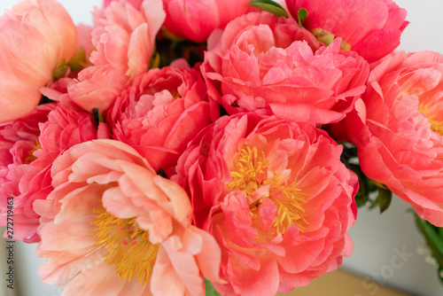 Fototapeta Naklejka Na Ścianę i Meble -  Coral peonies in a glass vase on wooden table.. Beautiful peony flower for catalog or online store. Floral shop concept . Beautiful fresh cut bouquet. Flowers delivery. Copy space