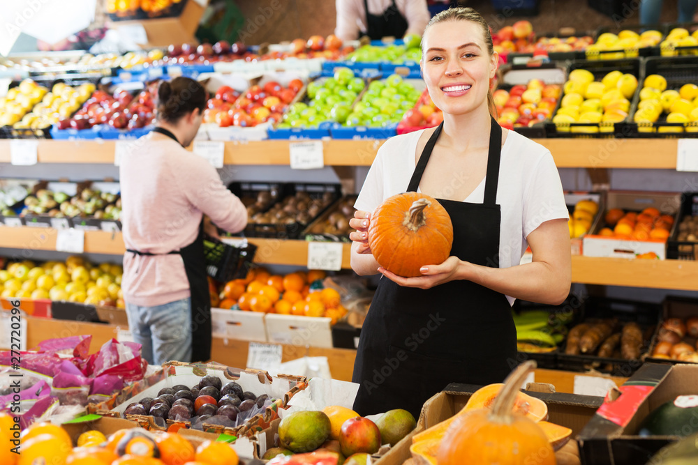Saleswoman offering pumpkin in supermarket