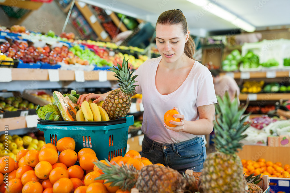 Woman standing with full shopping cart during shopping in fruit store