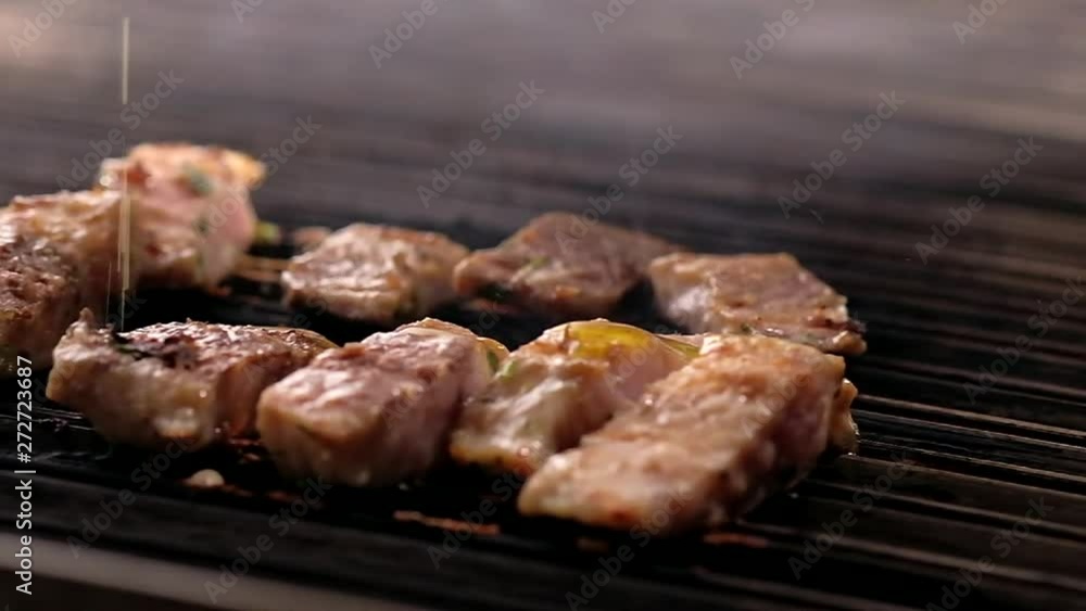 Moving camera slider showing cooking process of fish slices, close up view chef pouring olive oil on surgeon slices roasted on hot surface of barbecue grill Moving camera slider showing cooking process of fish slices, close up view chef pouring olive oil on surgeon slices roasted on hot surface of barbecue grill