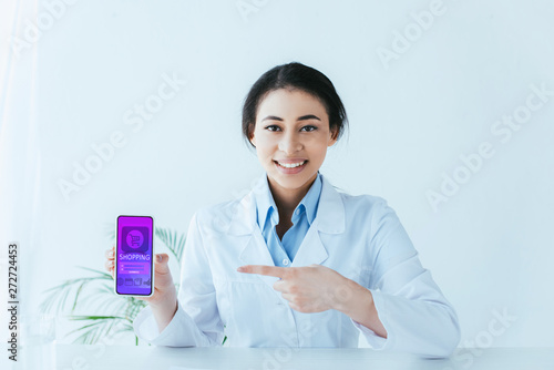 beautiful latin doctor showing smartphone with online shopping app on screen