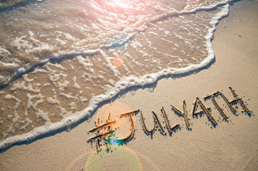 Modern message for the July 4th American holiday with a social media-friendly hashtag written in smooth sand with incoming wave on the beach