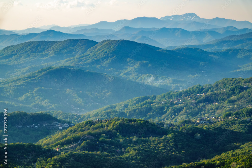 Layers of mountains in the haze during sunset. Beautiful sunset in the mountains. Beautiful sunset in a hilly valley with villages and fog in the lowlands. Layers of mountains in the haze during sunset. Beautiful sunset in the mountains. Beautiful sunset in a hilly valley with villages and fog in the lowlands.