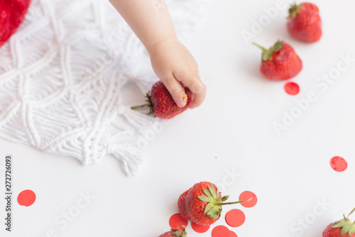 the child is holding strawberries. strawberry. child's hand