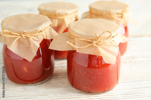 Jars of tomato sauce on wooden table, closeup