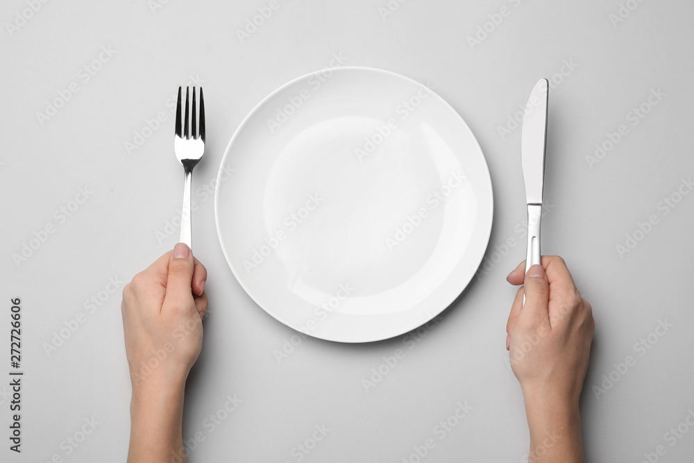 Woman with fork, knife and empty plate on grey background, top view - obrazy, fototapety, plakaty 