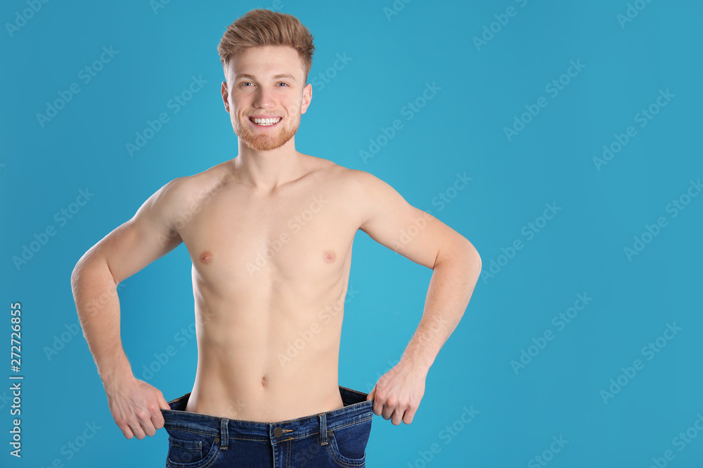 Handsome man in oversized jeans on color background. Space for text