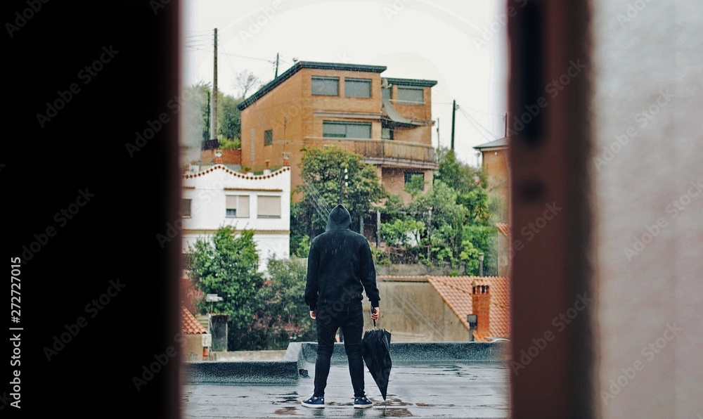 Man dressed in black under the rain.