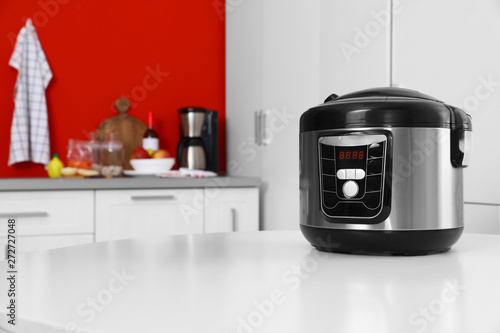 New modern multi cooker on table in kitchen. Space for text