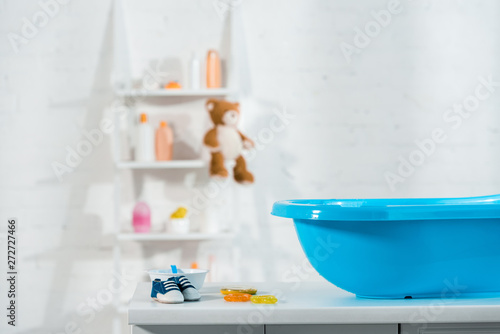 blue baby bathtub near baby sneakers and toys in bathroom